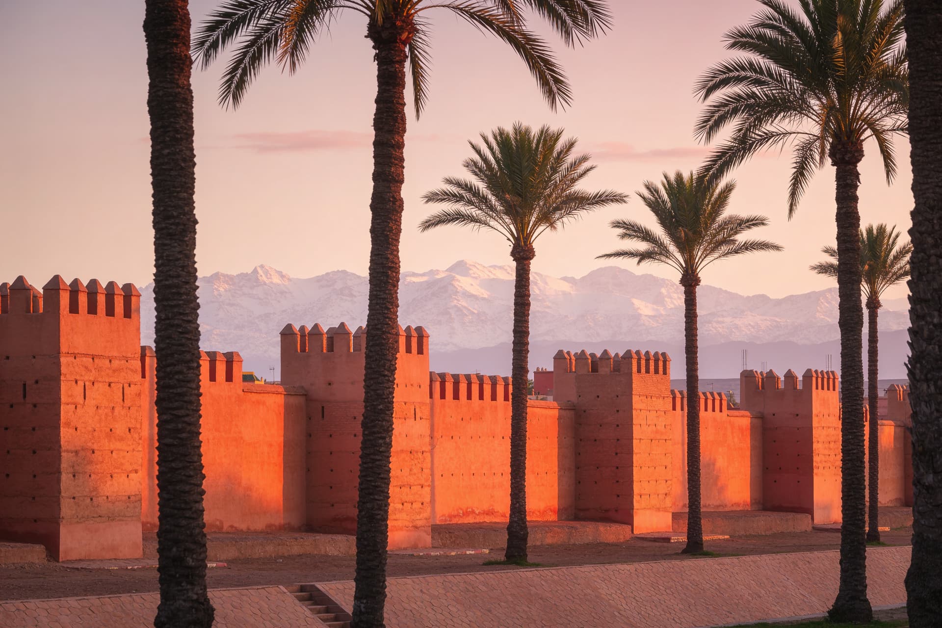 Remparts en pisé de Marrakech et palmiers au coucher du soleil